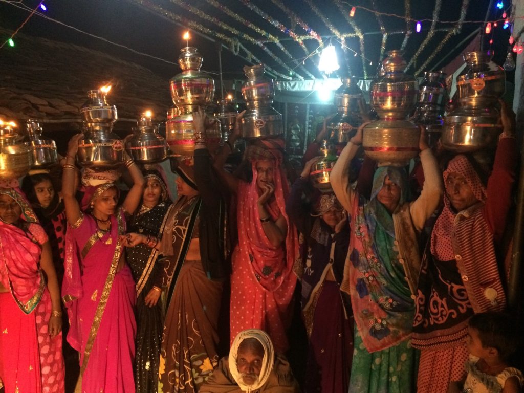 Indian women holding the traditional metal vases above their heads in honor of the Hindu wedding.