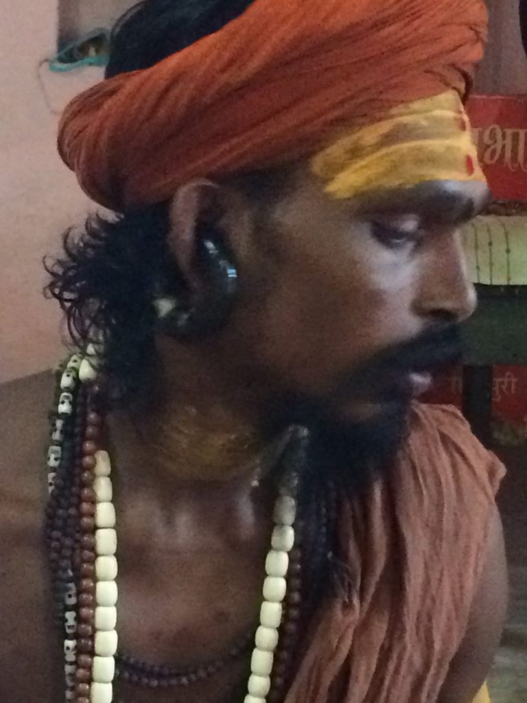 Adit Baba has a wide tube that goes through the cartilage of his ear, not through his earlobe (i.e., it's not an earlobe-stretching tunnel earring). Only the most powerful Babas wear have the privilege to pierce their ears like that.
